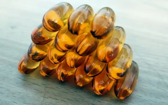 Amber softgel capsules stacked together on a pale grey surface