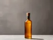 A plain unlabelled amber glass bottle with a pale stopper, standing on a grey stone surface